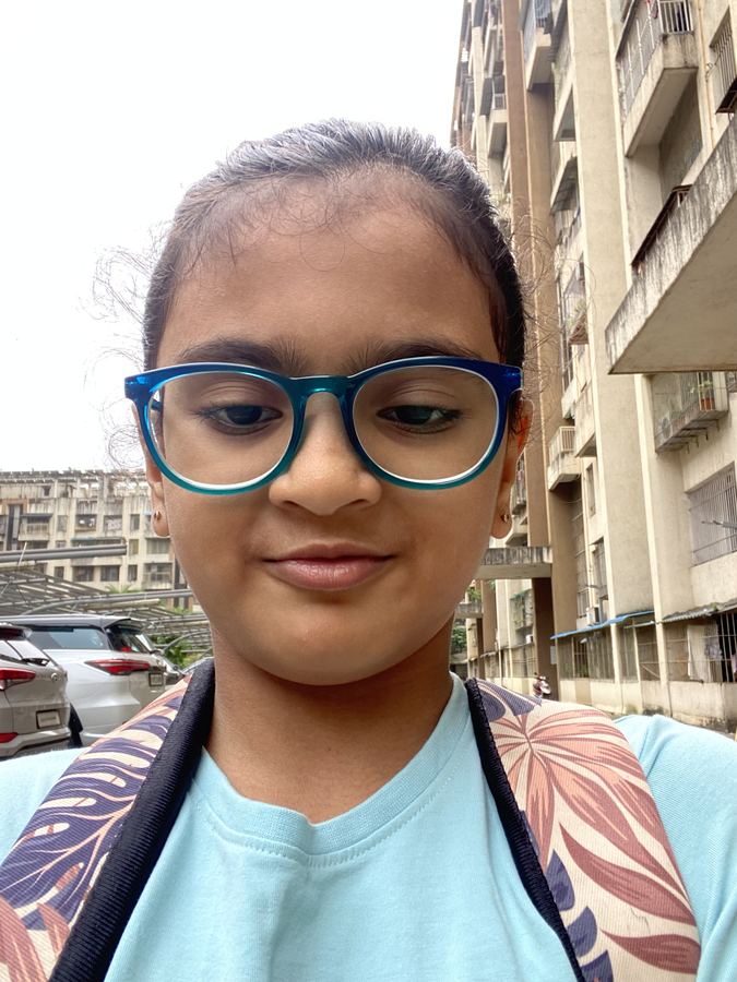 Smiling girl with blue glasses outside an apartment block